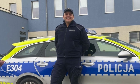 policjant stoi przy radiowozie policyjnym