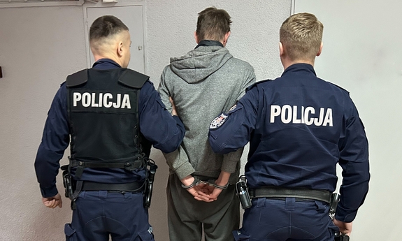 zatrzymany mężczyzna, zakuty w kajdanki, po bokach policjanci