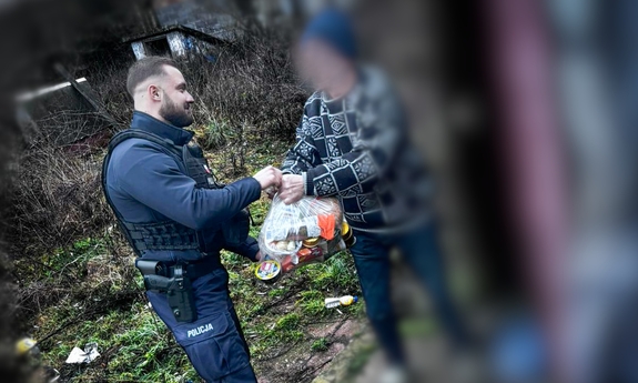 Policjant przekazuje reklamówkę z jedzeniem mężczyźnie