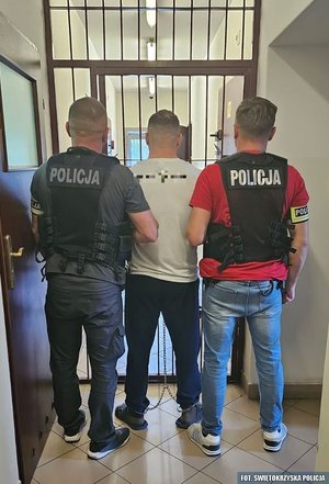 Policjanci prowadzą zatrzymanego przez korytarz