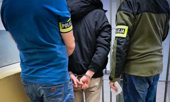 Policjanci prowadzą zatrzymanego przez korytarz