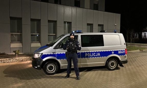 umundurowany policjant stoi przy radiowozie