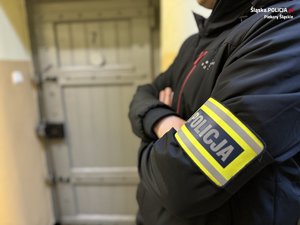 policjant mający na ramieniu opaskę z napisem Policja