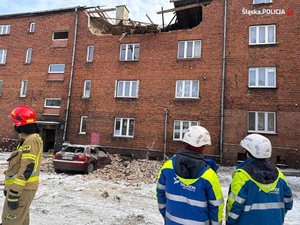 Kamienica, w której wybuchł gaz,  na pierwszym planie strażak i policjanci