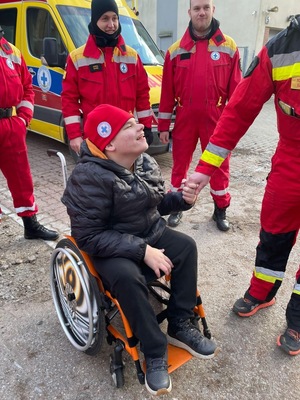 Chłopak na wózku inwalidzkim uśmiecha się do ratowników