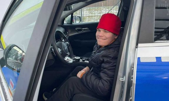 Chłopak siedzi za kierownicą w radiowozie