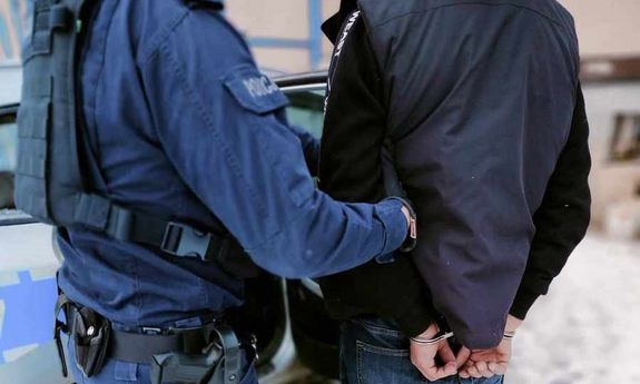 Policjant stoi z zatrzymanym przy radiowozie