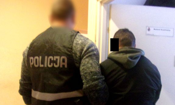 Policjant prowadzi zatrzymanego mężczyznę