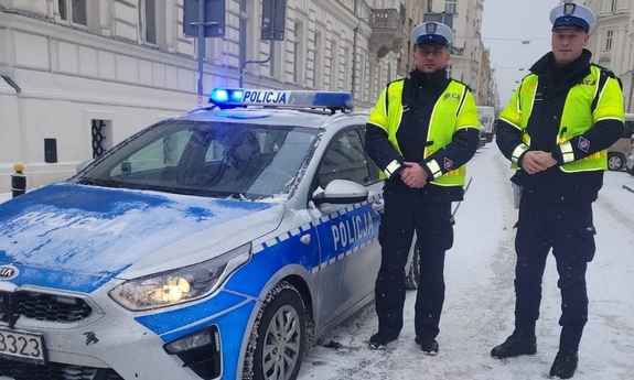 dwaj policjanci stoją przy radiowozie