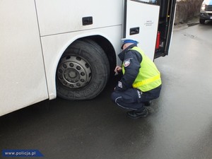 policjant sprawdza opony w autobusie