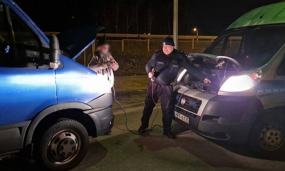 Policjant odpina kable rozruchowe po uruchomieniu drugiego pojazdu.
