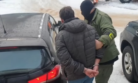 Policjant doprowadza zatrzymanego do radiowozu