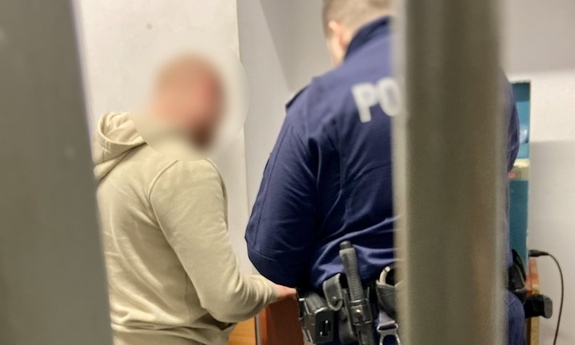 policjant wykonujący czynności z zatrzymanym mężczyzną