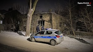 policjanci przy radiowozie i opuszczonym budynku