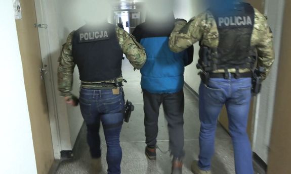 Dwóch policjantów prowadzi zatrzymanego przez korytarz