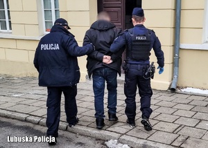 umundurowani policjanci prowadzą zatrzymanego mężczyznę