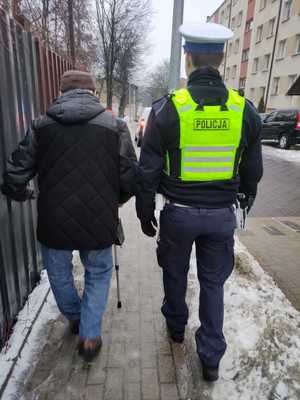 Policjant idzie chodnikiem z mężczyzną