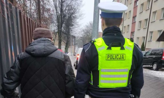 Policjant idzie chodnikiem z mężczyzną