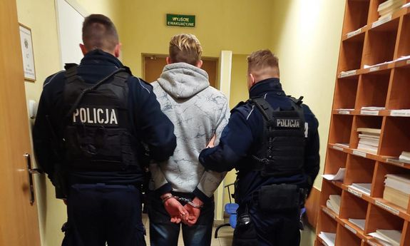 Policjanci prowadzą zatrzymanego przez korytarz