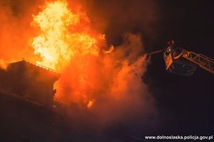 Pożar budynku - strażak gaszący pożar z podnośnika wozu strażackiego