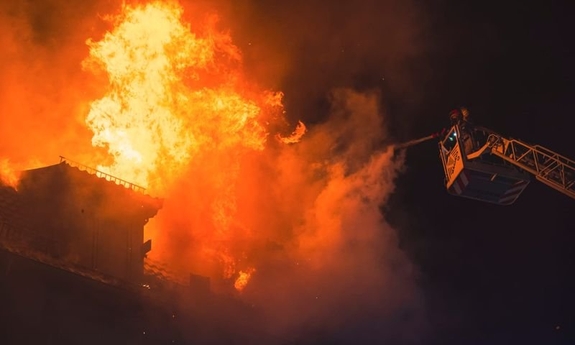 Pożar budynku - strażak gaszący pożar z podnośnika wozu strażackiego