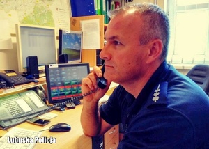 policjant siedzi przy biurku, rozmawia przez telefon