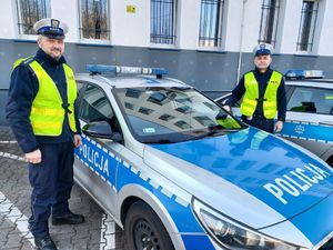dwaj policjanci stoją przy radiowozie