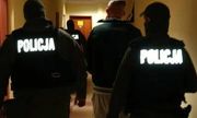 Policjanci prowadzą zatrzymanego przez korytarz