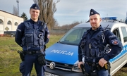 dwaj policjanci ogniwa patrolowo-interwencyjnego stoją przy radiowozie