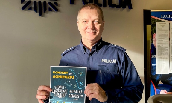 Policjant trzymający plakat dotyczący koncertu charytatywnego