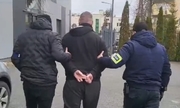 dwaj  nieumundurowani policjanci prowadzą zatrzymanego mężczyznę