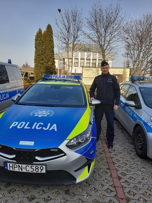 umundurowany policjant stoi przy radiowozach