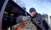 umundurowany policjant pomaga seniorce wsiąść do karetki