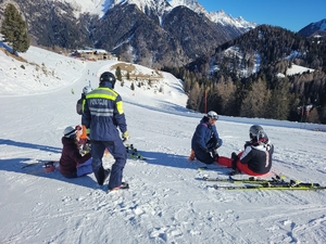 Dwóch policjantów udziela pomocy osobą na stoku narciarskim.