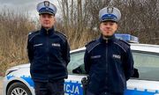 Dwóch policjantów stoi przed radiowozem