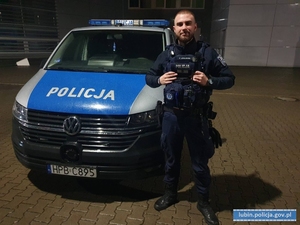 umundurowany policjant stoi przy radiowozie