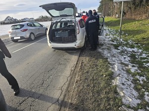 Na zdjęciu policjanci stoją przy zatrzymanym pojeździe