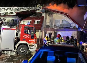 Strażacy na wysięgniku gaszą dach palącego się budynku