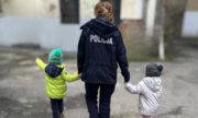 policjantka prowadzi za ręce dwojkę małych dzieci