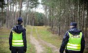 dwaj policjanci w żółtych kamizelkach w lesie