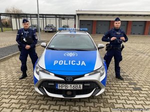 dwaj policjanci stoją przy radiowozie