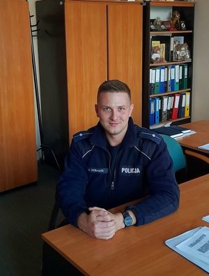 umundurowany policjant siedzi za stołem i pozuje do zdjęcia