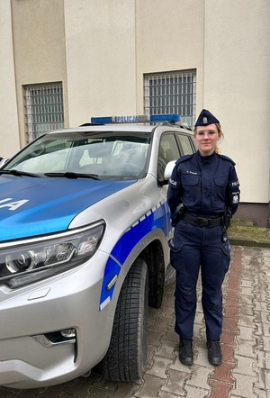 na zdjęciu widać jak umundurowana policjantka stoi przy radiowozie