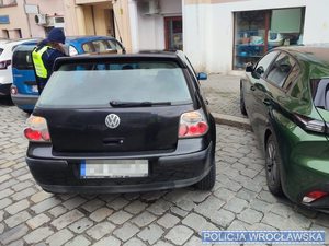 Tył samochodu, obok policjantka