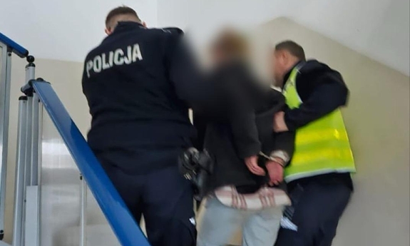 policjanci prowadzą zatrzymaną kobietę