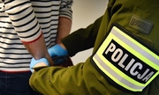 policjant zakłada na ręce zatrzymanego mężczyzny kajdanki
