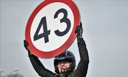 mężczyzna trzyma znak ograniczenia prędkości do 43 km/h