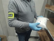 policjant trzyma w ręku worek z białą substancją