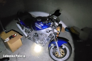 Niebieski motocykl w ciemnym garażu oświetlony latarką
