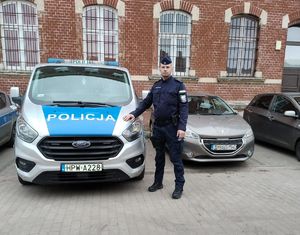 Policjant stoi przy radiowozie